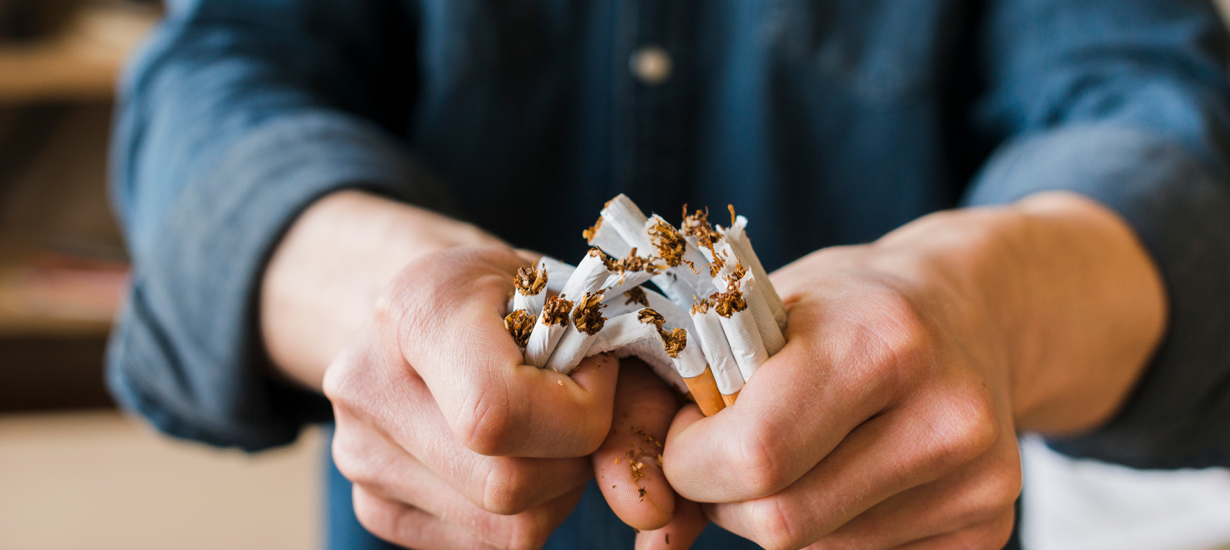 man-hands-breaking-bunch-cigarettes
